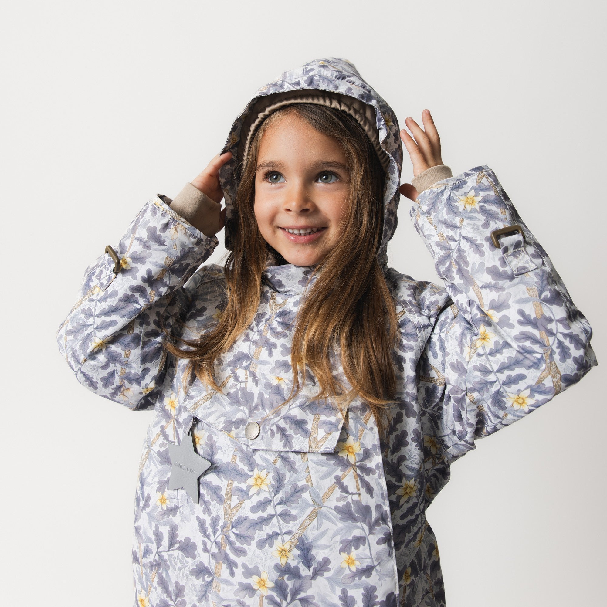 MATWANG fleece lined winter jacket in a hand-drawn Scandinavian floral print, shown with the detachable hood adjusted around the face and snow cuffs visible at the wrists.