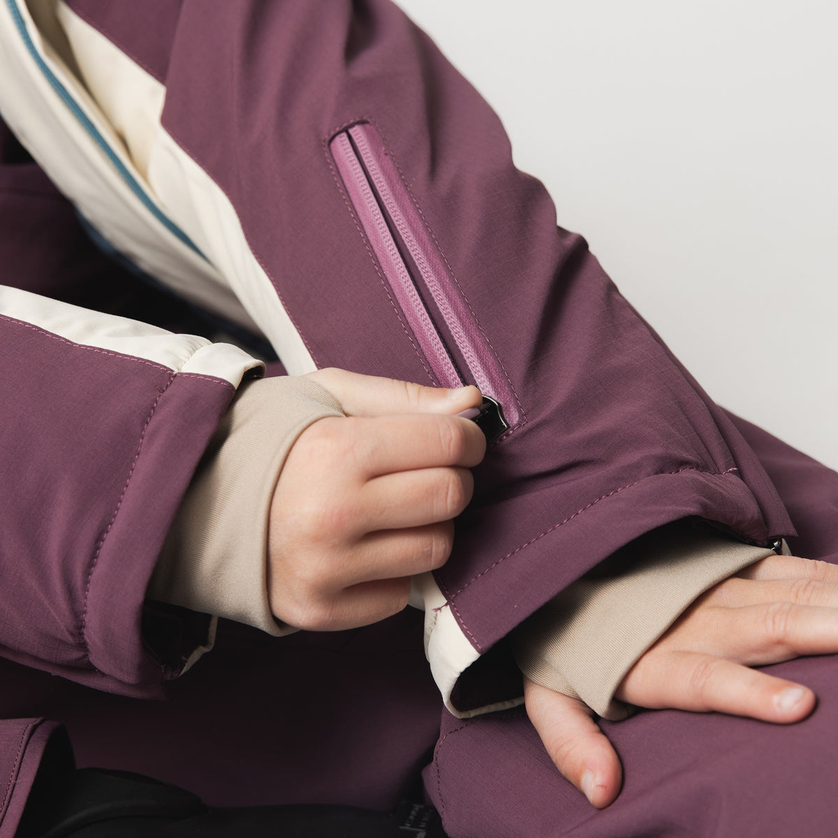 MATADANE ski tech jacket detail showing sleeve pocket with vertical zip closure in plum colourblock design, positioned for easy access to ski pass without opening the main jacket.